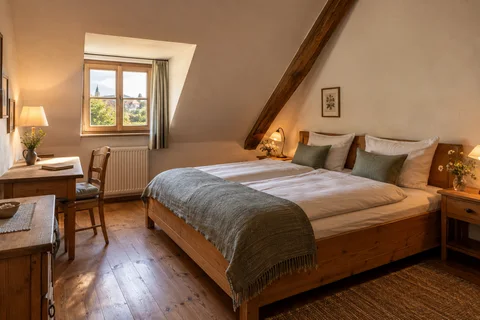 Die ruhige Giebelstube unter der Dachschräge mit altem Holzbalken.